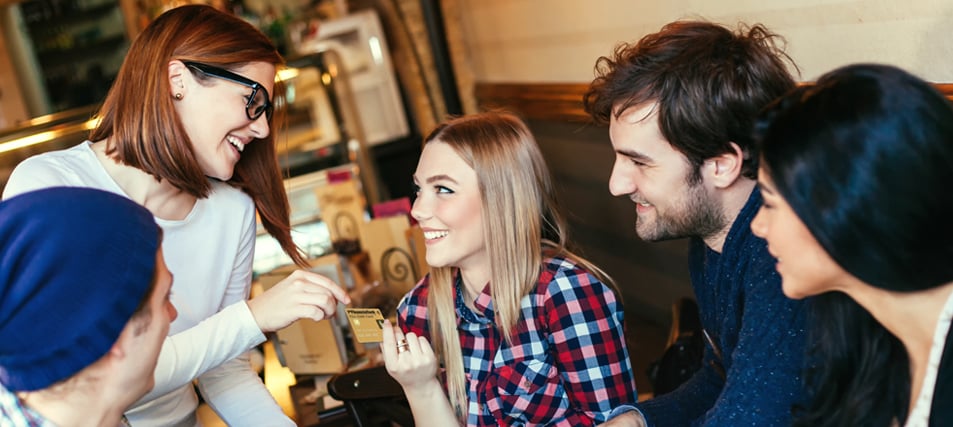 College student in restaurant handing credit card to waiter.