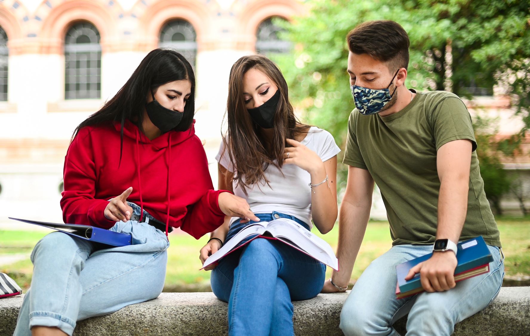Three college students studying together and wearing masks