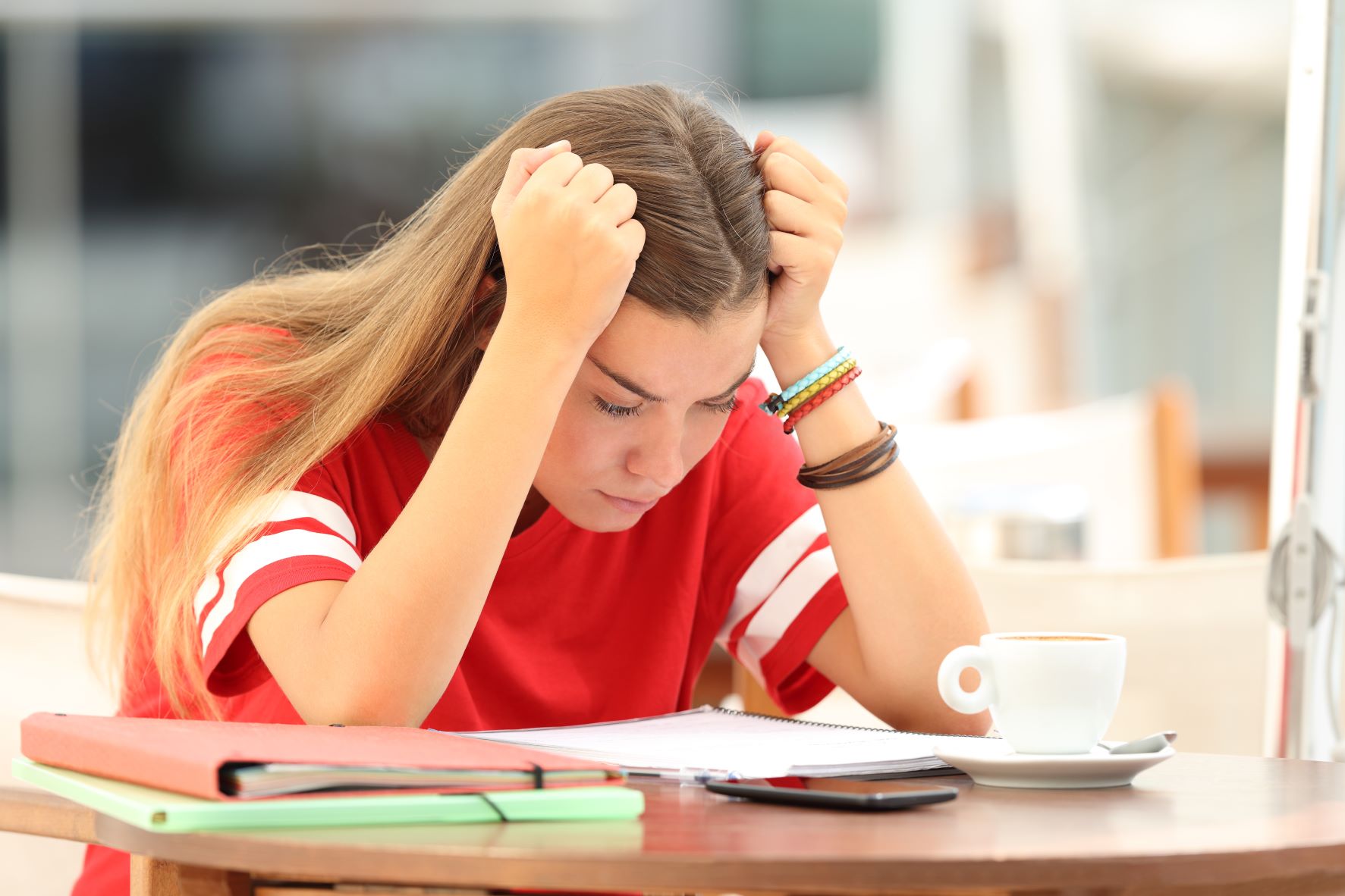 stressed student at desk with hands to temples