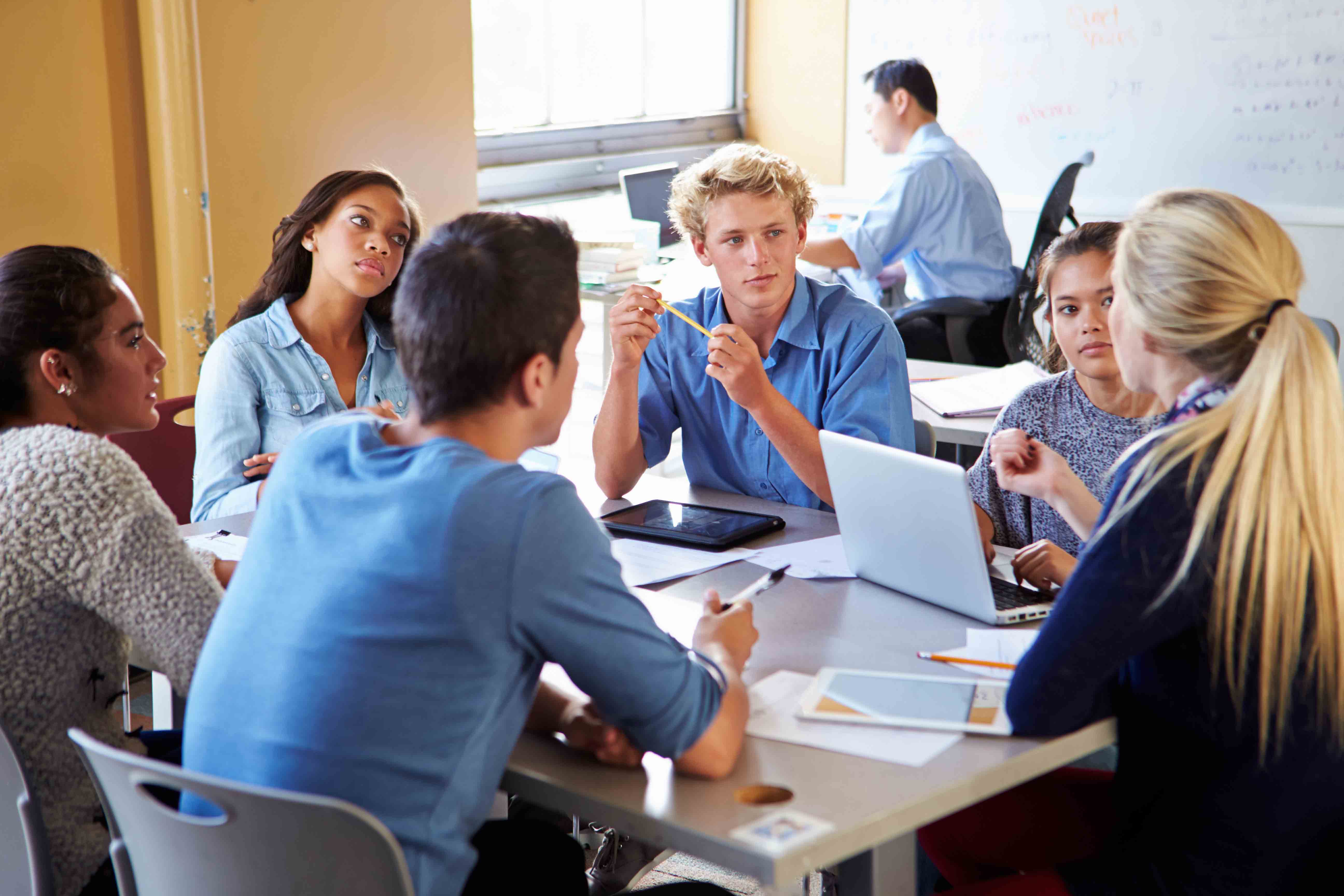 High school seniors sitting around table in classroom