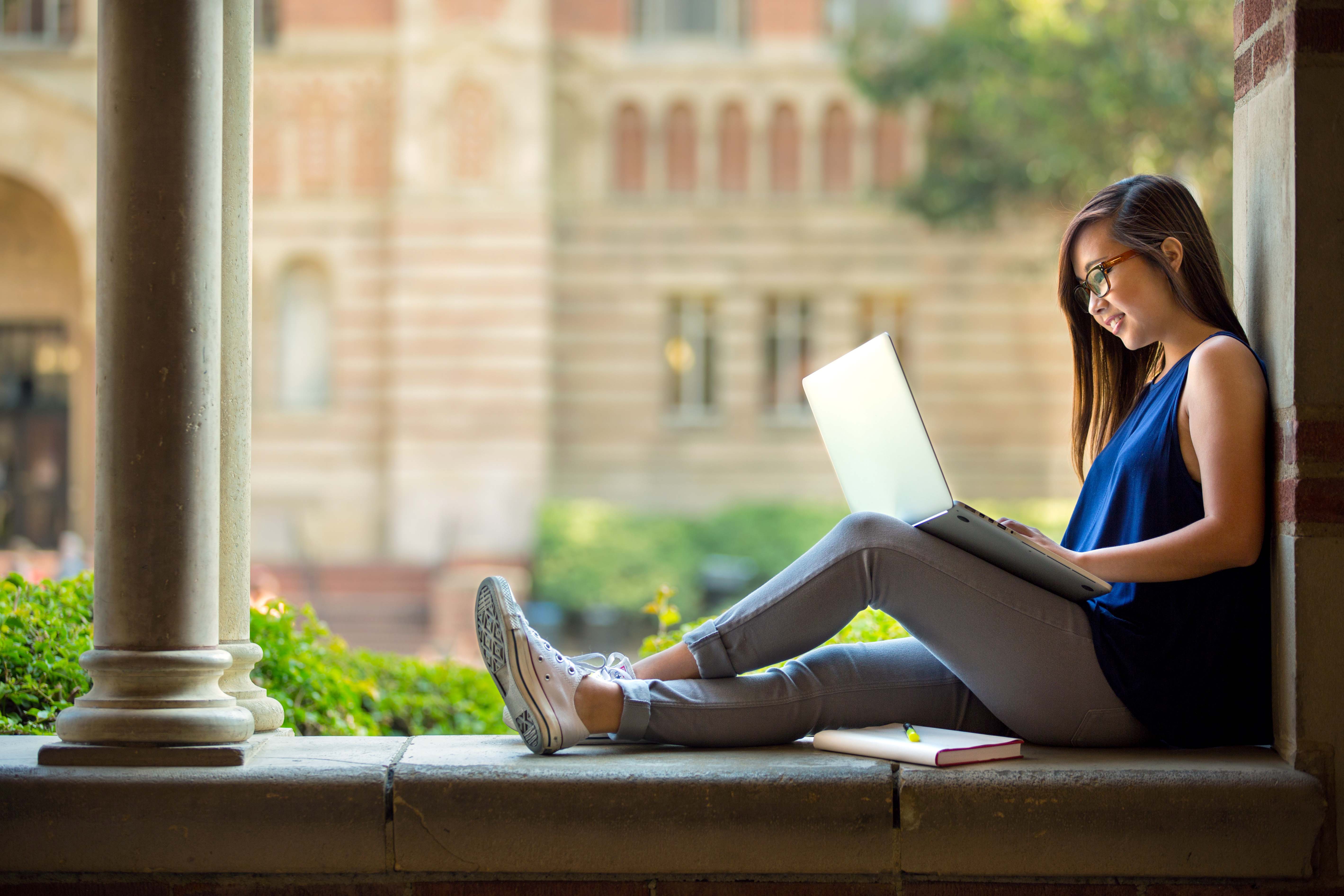 High school student working on laptop, ivy league college in background